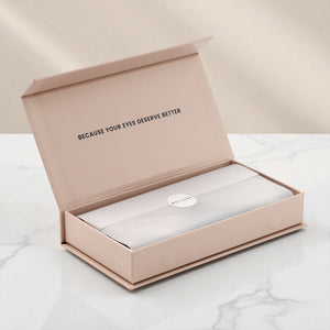 Open EYLUME Calm Heated Eye Mask box on a white marble surface with soft beige background, revealing the inner packaging and brand message “Because Your Eyes Deserve Better.”