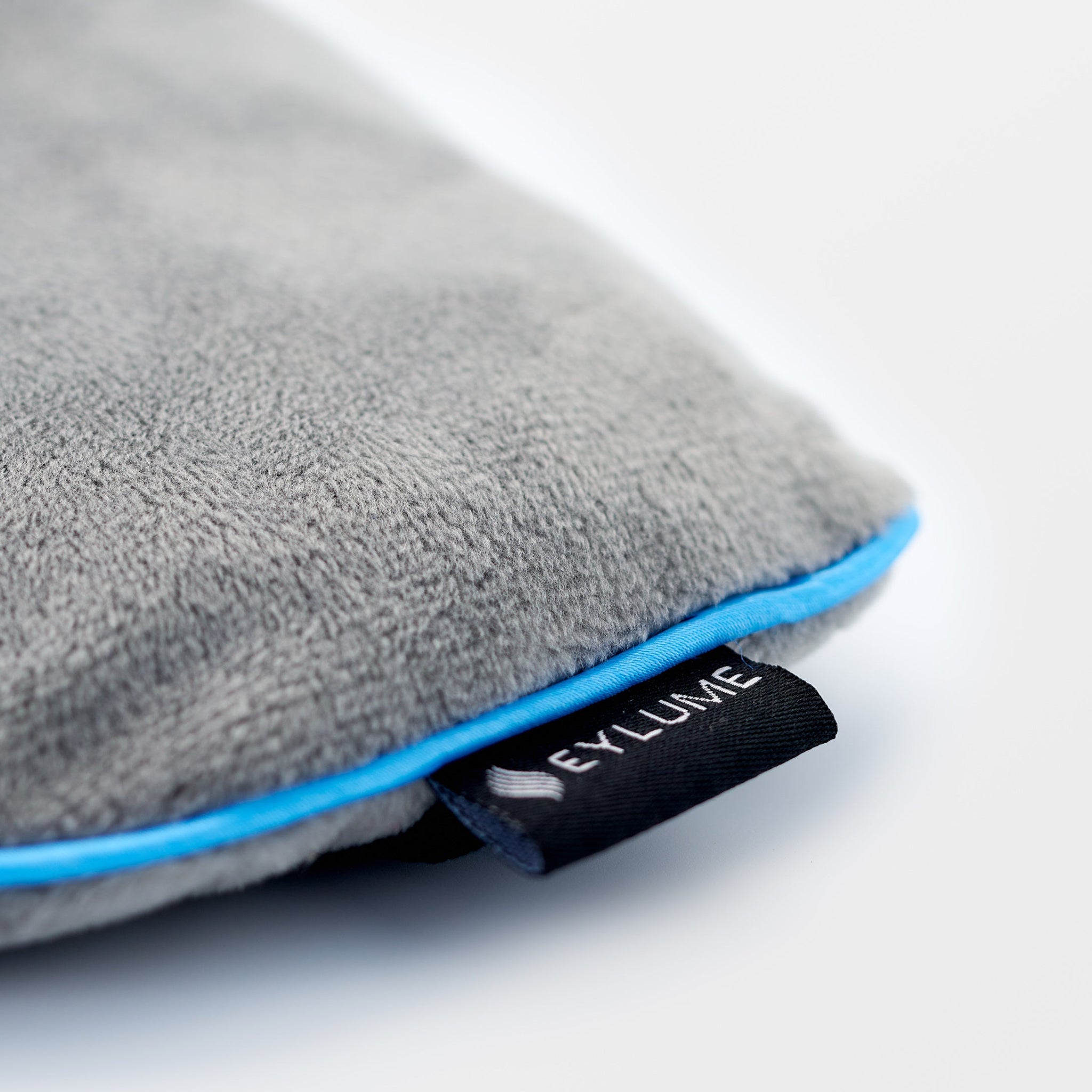 Close-up of EYLUME Calm Heated Eye Mask showing ultra-soft plush exterior and detailed logo tag